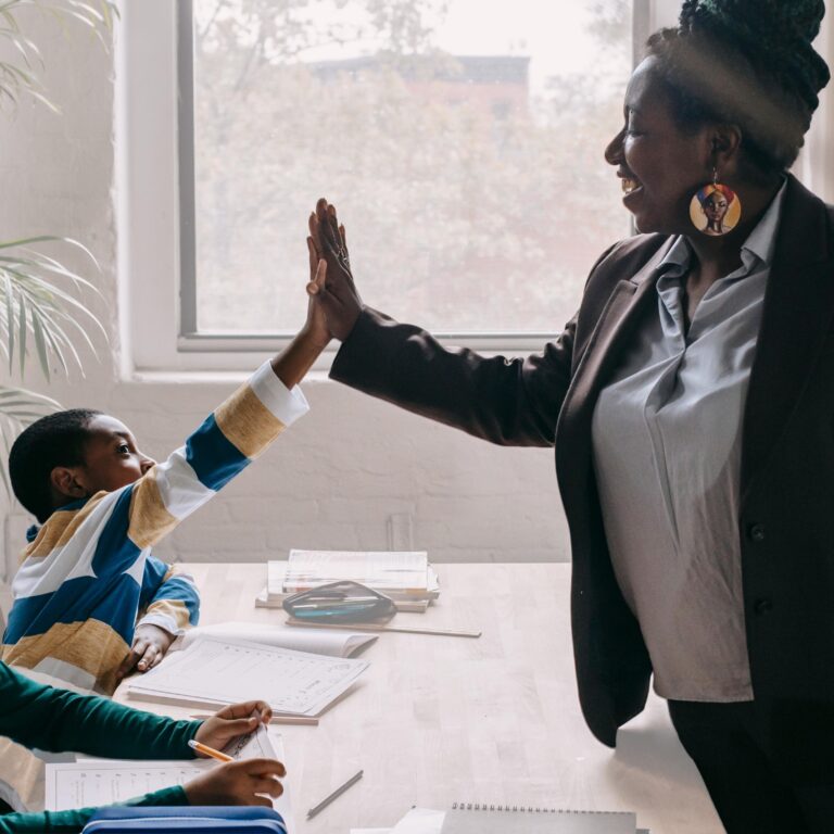 Black teacher supporting and high-fiving black student