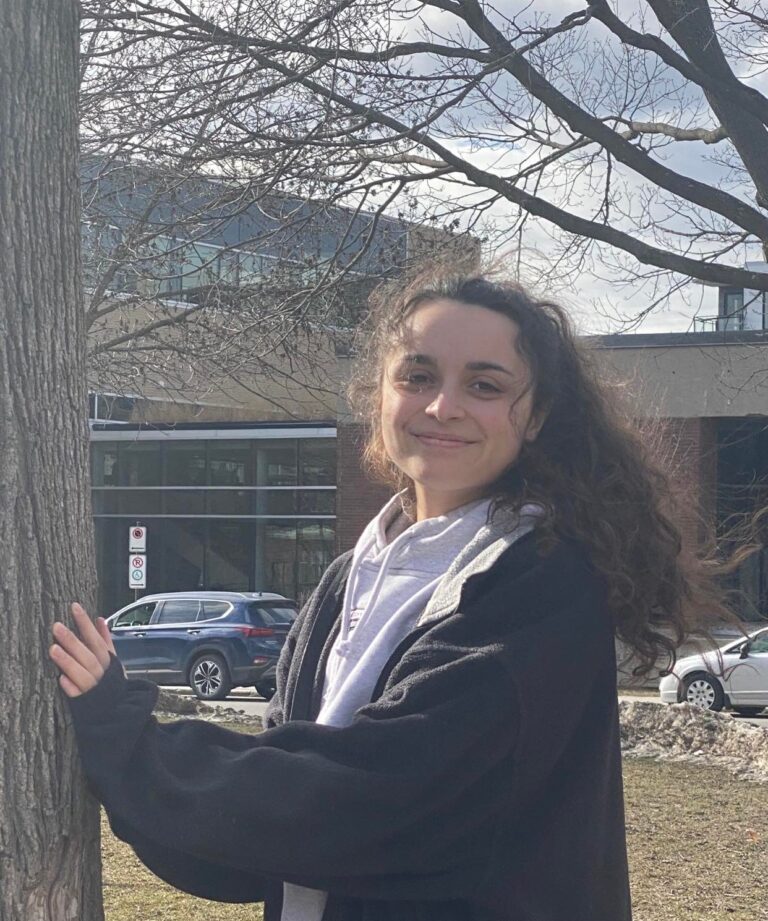 Panagiota Skoulikas standing by a tree in front of a school she went to as a student